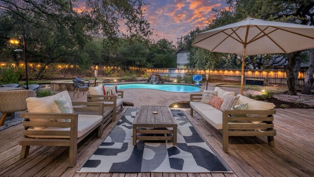 Eine Terrassenanlage im Freien mit Holzmöbeln, einem Pool und Lichterketten.