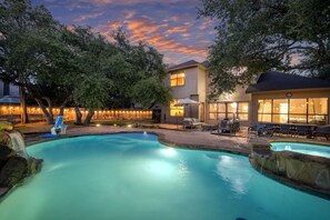 Un jardin avec une piscine, un panier de basketball et un espace patio aménagé avec du mobilier d’extérieur.