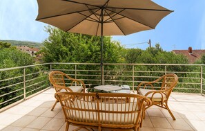 Enjoy a tranquil outdoor space with a table, two chairs, and a large umbrella, surrounded by lush greenery and distant views.