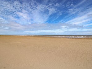 A wide sandy beach with gentle waves and a partly cloudy sky. - Mariai Eton Road (Mablethorpe)