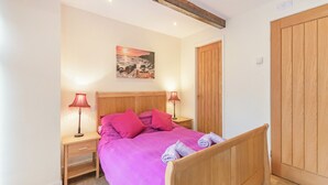 Ein Schlafzimmer mit einem hölzernen Bett, zwei Nachttischen mit Lampen, einem Holzschrank und einem Bild an der Wand.