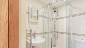 Ein modernes Badezimmer mit einer begehbaren Glasdusche, einem Waschbecken und einer Toilette.