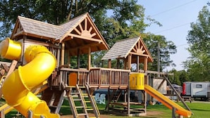 A playground with a yellow slide and wooden play structures. - LAKEFRONT COTTAGE #5 - PRINCE EDWARD COUNTY - LAKE CONSECON RESORT (Prince Edward)