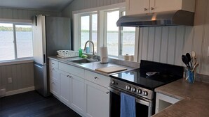 A kitchen with a large window, a stove, and a sink. - LAKEFRONT COTTAGE #5 - PRINCE EDWARD COUNTY - LAKE CONSECON RESORT (Prince Edward)