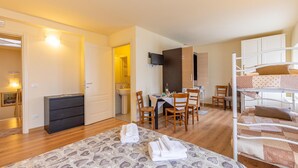 Habitación de hotel con cama, escritorio con silla, televisor y litera.