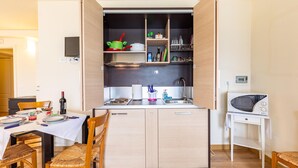 Una cocina compacta con armarios de madera, un microondas integrado y un comedor con mesa y sillas.