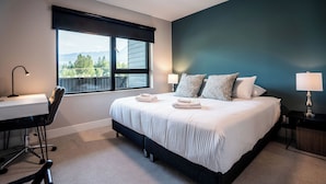 A bedroom with a large bed, a desk, and a chair. - Northern Exposure by Revelstoke Vacations (Revelstoke)