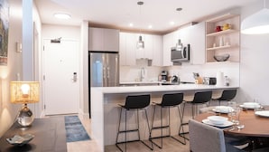 A modern kitchen with a central island, bar stools, and a dining table set for four. - Northern Exposure by Revelstoke Vacations (Revelstoke)