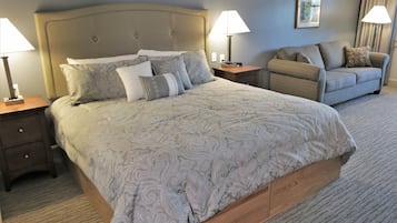 Ein Hotelzimmer mit einem großen Bett, einer Couch, zwei Nachttischen mit Lampen und einem gerahmten Bild an der Wand.
