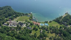 An aerial view of a coastal property with a tennis court, a dock, and a marina.