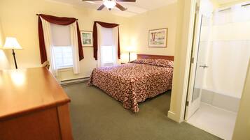 A bedroom with a bed, a ceiling fan, a door, and a window with curtains.