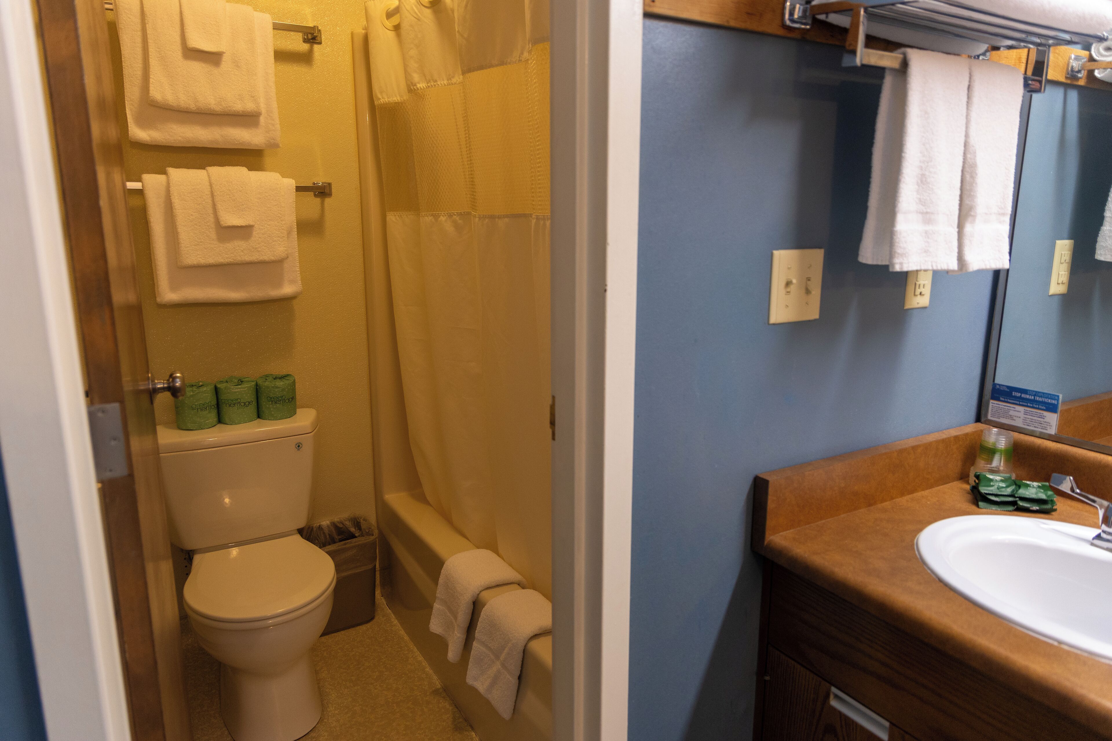 Une salle de bain avec des toilettes, une douche et un lavabo. Des serviettes sont accrochées au mur et un miroir se trouve au-dessus du lavabo.