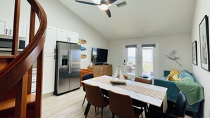 A modern kitchen with a built-in refrigerator, wooden cabinets, and a dining area with a table and chairs.