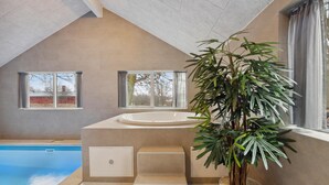 A modern bathroom with a bathtub, a sink, and a large potted plant. - Luxurious home in Krakow am See (Krakow am See)