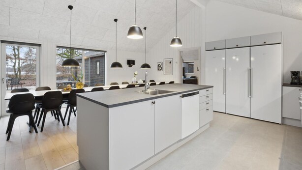 A modern kitchen with a central island, white cabinetry, and pendant lighting. - Luxurious home in Krakow am See (Krakow am See)