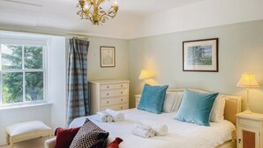 A neatly arranged bedroom with a large bed, bedside lamps, a chest of drawers, a bench, and a window with curtains. - The Old Manse - UKC6854 (Glenclova, near Kirriemuir)