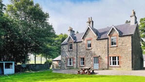 A stone building with multiple windows and a grassy lawn. - The Old Manse - UKC6854 (Glenclova, near Kirriemuir)