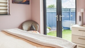 A bedroom with a bed, a chair, a heater, and a sliding glass door leading to a balcony.
