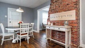 A dining area with a white table and chairs, a brick wall, and a sign with text.