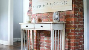 A rustic brick wall with a sign that reads "Come as you are."