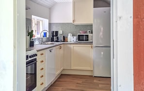 A kitchen with a microwave, toaster, coffee maker, and a refrigerator.
