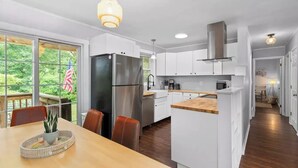 A modern kitchen with white cabinets, stainless steel appliances, and a wooden dining table.