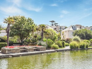 A serene garden with a pond, stone steps, and a variety of plants and flowers. - The Annex at Tenniside (Perranporth)