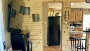 A modern kitchen with wooden walls, a black refrigerator, and a dining area with bar stools.