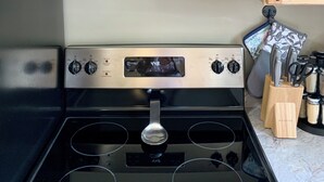 A kitchen with a stainless steel range hood, a digital clock, and wooden cabinets.