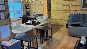 A cozy living area with a wooden interior, a dining table with benches, a sofa, and a coffee table.
