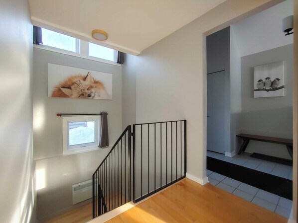 A staircase with a black railing, a small window, and a picture of a fox on the wall.