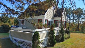 A two-story house with a balcony, surrounded by trees and a fenced yard. - Chalet Escapade Orford - Great golf and ski escape 5 minutes from Mont-Orford (Orford)