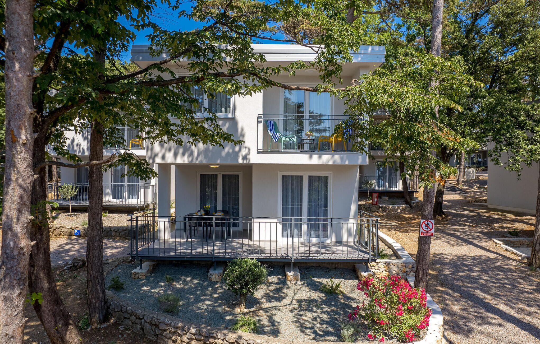 Un immeuble de deux étages doté d’un balcon, d’un petit jardin et d’un panneau indiquant qu’il est interdit de fumer.