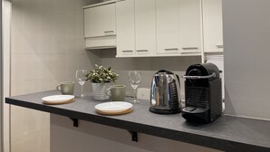 A kitchen counter with a coffee maker, a kettle, and a potted plant. - Housing Sol by Sharing Co (Madrid)