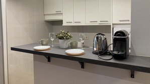A modern kitchen with white cabinets, a black countertop, and a coffee machine. - Housing Sol by Sharing Co (Madrid)