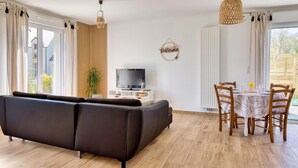 Ein modernes Wohnzimmer mit einer Couch, einem Fernseher, einem Esstisch und Stühlen.