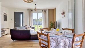 Ein modernes Wohnzimmer mit einer Couch, einem Esstisch mit Gläsern und Blick ins Freie.