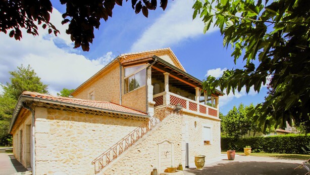 Un edificio in pietra con un balcone, una scala e piante in vaso.