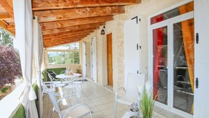 Una veranda coperta con posti a sedere all'aperto, pareti in pietra e ampie finestre.