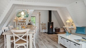 Une pièce mansardée chaleureuse, aménagée avec une table à manger, des chaises, un canapé, une cheminée et une lampe.