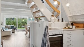 Une cuisine moderne avec des meubles blancs, un four encastré et un coin repas comprenant une table et des chaises.