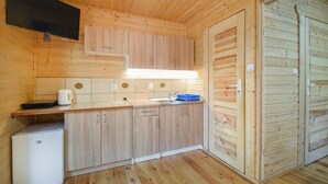 A compact wooden cabin with a kitchenette, a television mounted on the wall, and a door with a handle. - 1 bedroom awesome apartment in Pogorzelica (Pogorzelica)