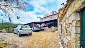 Un bâtiment en pierre doté d’un espace extérieur couvert et de places de stationnement pour voitures.