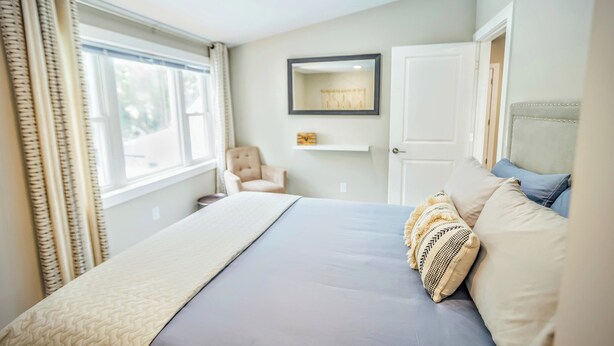 Une chambre à coucher avec un lit, une chaise, un miroir et une porte.