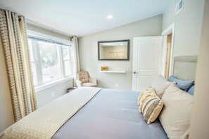 A bedroom with a bed, a chair, a mirror, and a door. - 4-bedroom in-ground pool 10 minutes to Downtown Grand Rapids and GRR Airport (Grand Rapids)