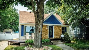 A two-story house with a blue roof, a brick section, and a front porch.