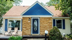 Une maison à deux étages avec un toit bleu, une porte d’entrée dotée d’un panneau de verre et une boîte aux lettres.