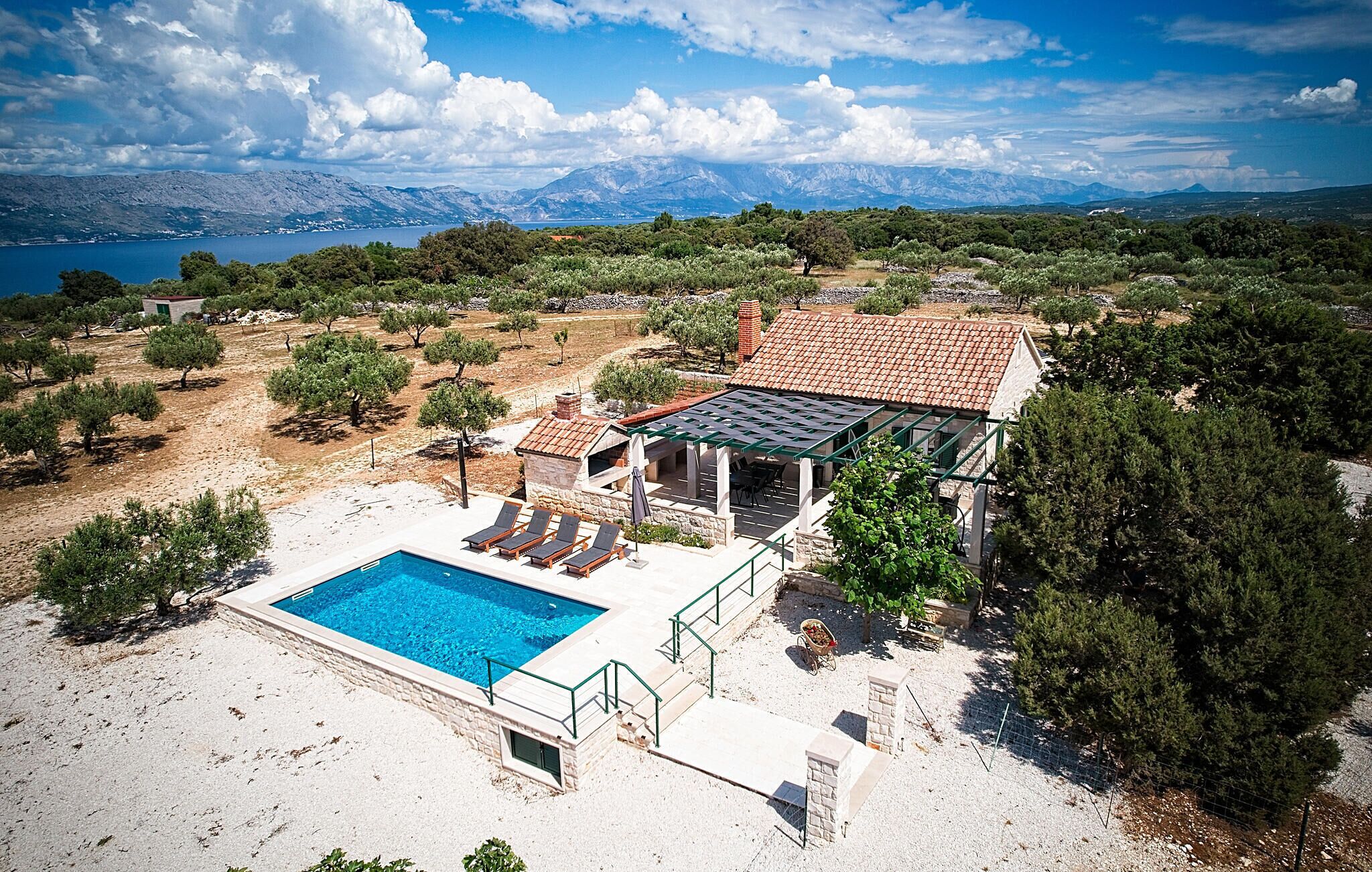 Una villa con piscina, mobiliario exterior y vistas al mar y a las montañas.