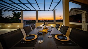 An outdoor dining area with a table set for two, overlooking a sunset view. - Beautiful home in Pucisca - Praznica (Pucisca - Praznica)