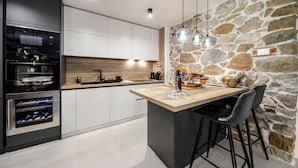 A modern kitchen with a stone accent wall, built-in appliances, and a bar area with stools.